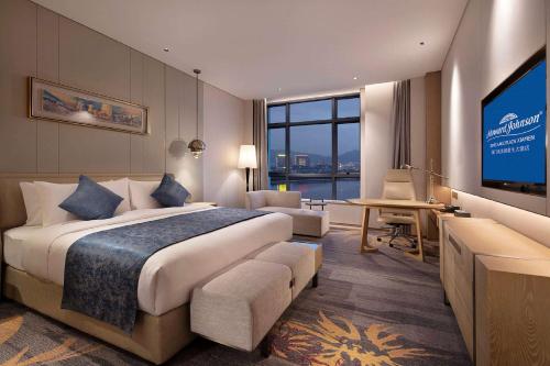 廈門市にあるHoward Johnson by Wyndham Jimei Lake Plaza Xiamenの大型ベッド1台、薄型テレビが備わるホテルルームです。