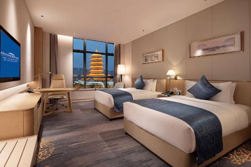 a hotel room with two beds and a flat screen tv at Howard Johnson by Wyndham Jimei Lake Plaza Xiamen in Xiamen
