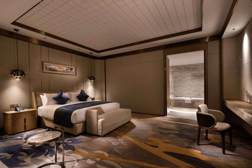 a bedroom with a bed and a couch and a window at Howard Johnson by Wyndham Jimei Lake Plaza Xiamen in Xiamen