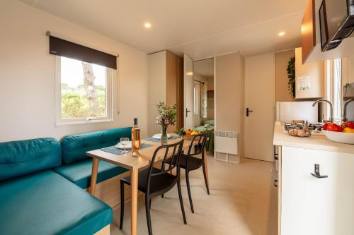 - un salon et une cuisine avec un canapé bleu et une table dans l'établissement Le Pinédou, mobil-home niché sous les pins avec jolie vue mer, à Hyères