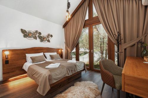 a bedroom with a bed and a desk and a window at Toplik Village Resort in Lukavica