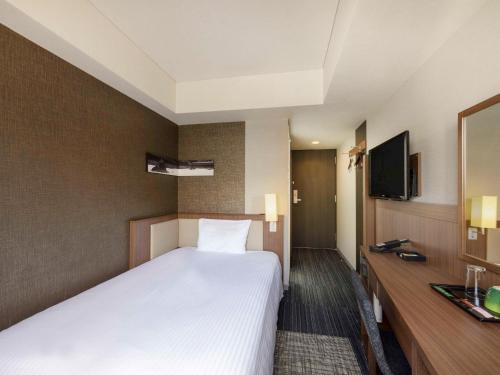 京都市にあるイビススタイルズ京都四条のベッドとテレビが備わるホテルルームです。