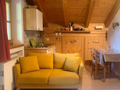 eine gelbe Couch in einer Küche mit einem Tisch in der Unterkunft Ferienwohnungen Monika Kloiber in Ruhpolding