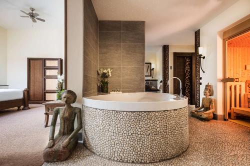 ein Badezimmer mit einer Badewanne mit zwei Statuen um ihn herum in der Unterkunft Park-Hotel Hagenbeck in Hamburg