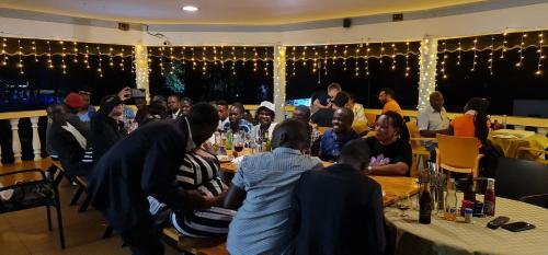 a group of people sitting at tables in a restaurant at Northern Pearl in Gulu