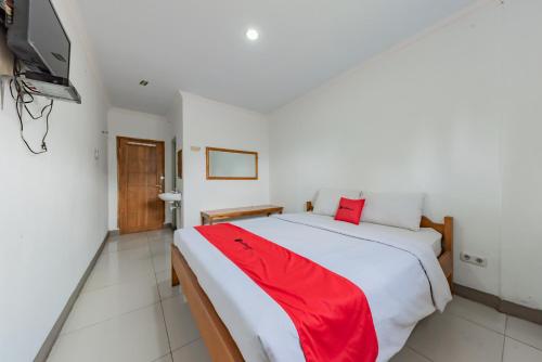 a bedroom with a large bed with a red blanket at RedDoorz Syariah at Pantai Pelabuhan Ratu in Sukabumi