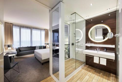 a bathroom with a bed a sink and a mirror at Lindner Hotel Dusseldorf Seestern, part of JdV by Hyatt in Düsseldorf