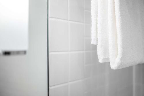 a bathroom with a shower and a white towel at Lindner Hotel Dusseldorf Seestern, part of JdV by Hyatt in Düsseldorf