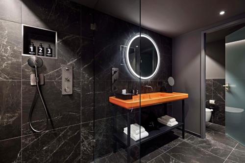 a bathroom with a shower and a sink and a mirror at Lindner Hotel Dusseldorf Seestern, part of JdV by Hyatt in Düsseldorf