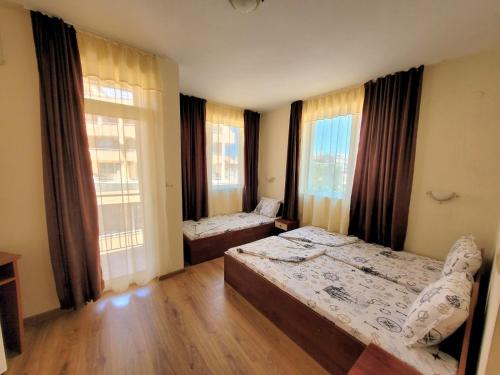 a bedroom with two beds and two windows at Guesthouse Iceberg in Ravda