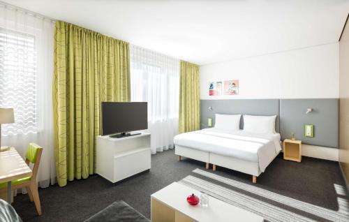 a hotel room with a bed and a tv at Lindner Hotel Frankfurt Sportpark, part of JdV by Hyatt in Frankfurt/Main