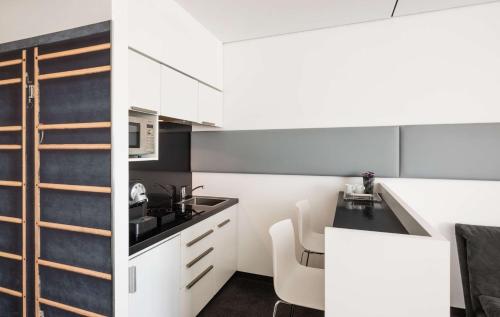 a kitchen with white cabinets and a black counter top at Lindner Hotel Frankfurt Sportpark, part of JdV by Hyatt in Frankfurt/Main