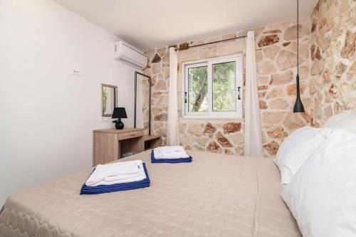 a bedroom with a large bed with a stone wall at Villa Maria in Laganas