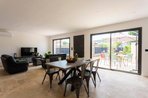 un salon avec une table et des chaises en bois dans l'établissement La Villa de l'Olivier - Maison climatisée pour 6, à Saint-Victor-la-Coste