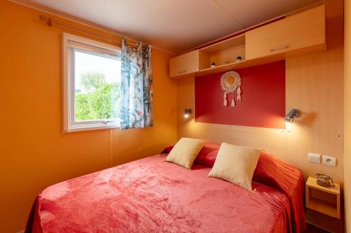 a bedroom with a red bed with a window at L'Estrellus, mobil-home climatisé au cœur du vignoble à quelques mètres de la mer in Hyères