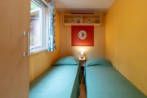 two beds in a room with a window at L'Estrellus, mobil-home climatisé au cœur du vignoble à quelques mètres de la mer in Hyères