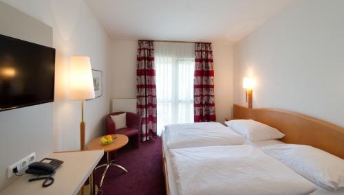 a hotel room with two beds and a television at Altmann's Stube in Erlangen
