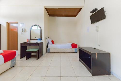 a room with two beds and a desk and a mirror at RedDoorz @ Jalan R.E. Martadinata Sukabumi in Sukabumi