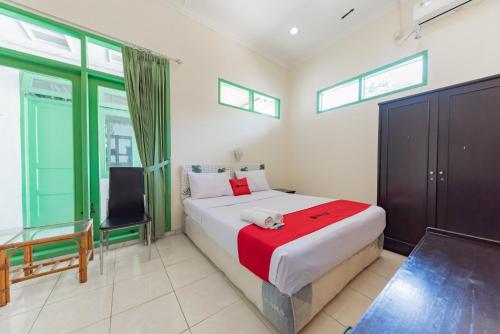 1 dormitorio con 1 cama, 1 silla y ventanas en RedDoorz @ Jalan R.E. Martadinata Sukabumi en Sukabumi