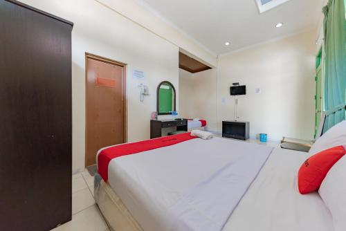 a bedroom with a large white bed and a television at RedDoorz @ Jalan R.E. Martadinata Sukabumi in Sukabumi