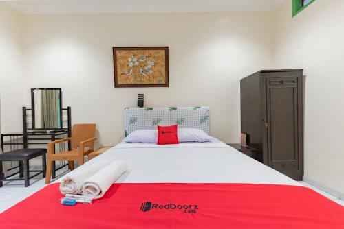 a bedroom with a large bed with a red towel on it at RedDoorz @ Jalan R.E. Martadinata Sukabumi in Sukabumi