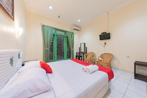 a bedroom with a white bed and a television at RedDoorz @ Jalan R.E. Martadinata Sukabumi in Sukabumi