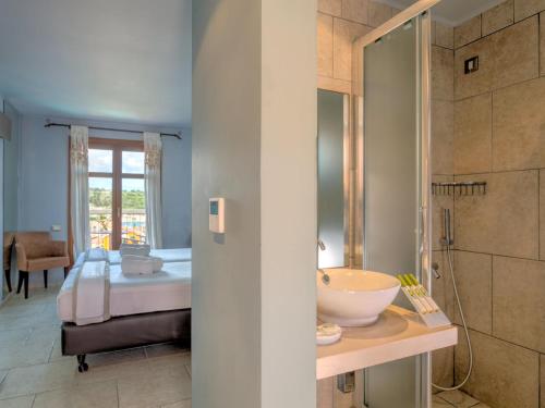 a bathroom with a bed and a sink in a room at Fiscardo Bay Hotel in Fiskardho