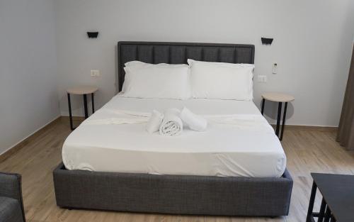 a bed with white sheets and towels on it at Palm Side Hotel in Vlorë