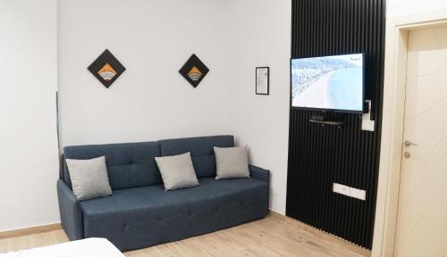 a living room with a blue couch and a flat screen tv at Palm Side Hotel in Vlorë