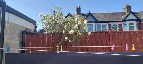 a fence in front of a house with a tree at Newport rental property Furnished studio near train station Free Wifi Parking in Newport
