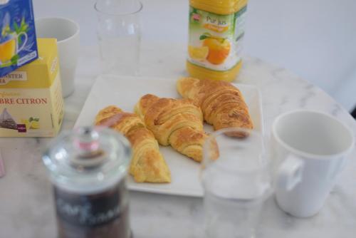 a plate of croissants on a table with a cup at Boho Chic-27m²-Proche de Paris in Cergy