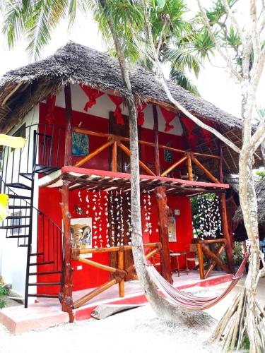 a red building with a hammock in front of it at Karibu Paradaizi in Michamvi