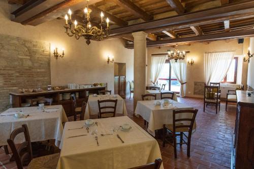 un restaurante con mesas y sillas blancas y una lámpara de araña en Locanda di Montegiove, en Fano