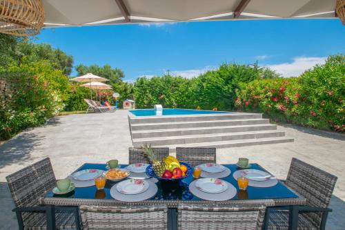 a table with a bowl of fruit on it at Villa Andreas A Private Paradise in Mouzákion