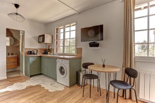 une cuisine avec un lave-linge, une table et des chaises dans l'établissement Le Normand- Bois d'arcy, à Bois-dʼArcy