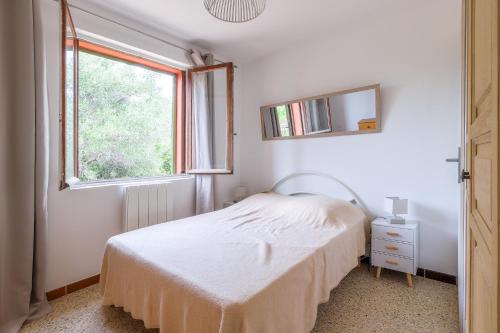 a white bedroom with a bed and a window at Calenzana Cinque - Appt avec piscine partagée in Calvi