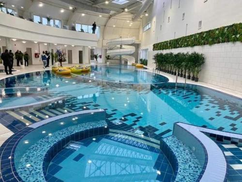 a large swimming pool with blue water in a building at Cabana Soral Baile Figa in Beclean