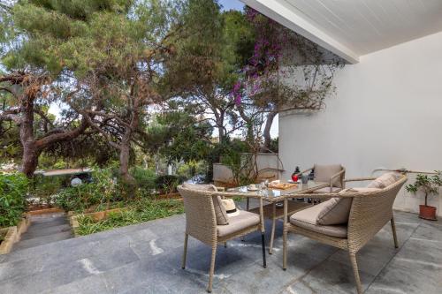 eine Terrasse mit einem Tisch, Stühlen und Bäumen in der Unterkunft Secret Aktis by BluPine in Athen