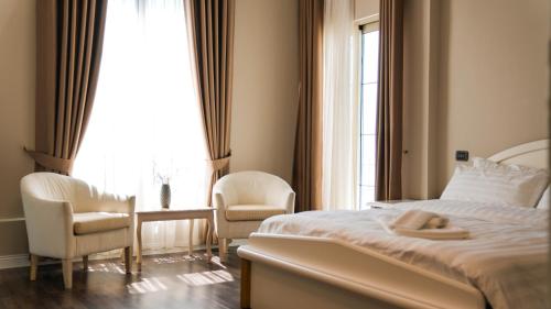 a bedroom with a bed and two chairs and a window at Hotel Majestic in Durrës