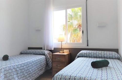 a bedroom with two beds and a window at Apartamento 3H primera linea de mar y piscina GM 2 424 in Pals