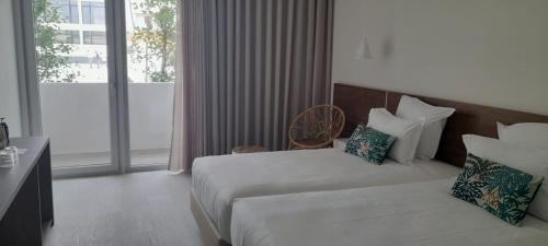 a hotel room with a bed and a large window at Porto Covo Praia Hotel & SPA in Porto Covo