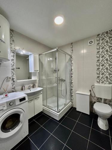 ein Bad mit einer Dusche und einer Waschmaschine in der Unterkunft Victoria Apartment Skopje in Skopje