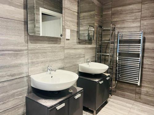 a bathroom with two sinks and a mirror at ABRIDGE PANORAMIC House in Theydon Bois