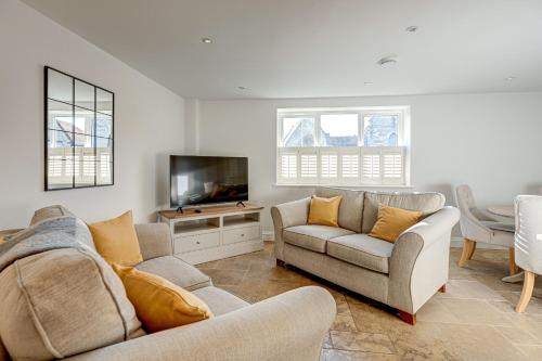 a living room with two couches and a flat screen tv at Friday Cottage in Wheatley