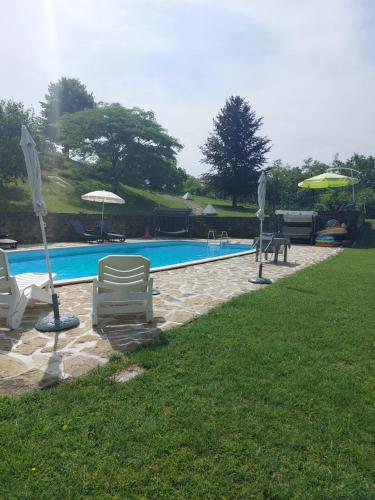 una piscina con sillas y sombrillas en un patio en appartamento con piscina tra la colline, en San Cristoforo