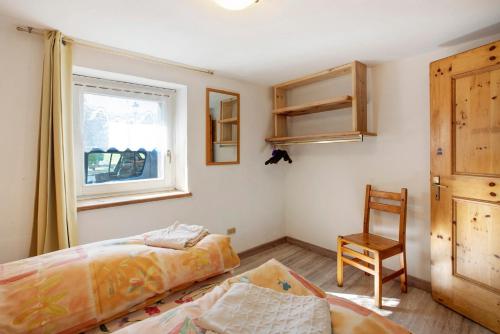 um quarto com uma cama, uma cadeira e uma janela em Casa Valentina em Livigno