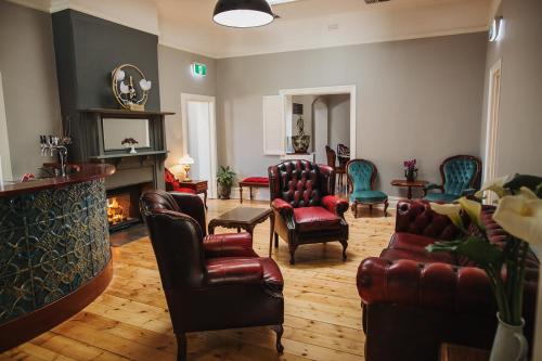 a living room with leather chairs and a fireplace at Penobscot Farm Cottage in Watervale