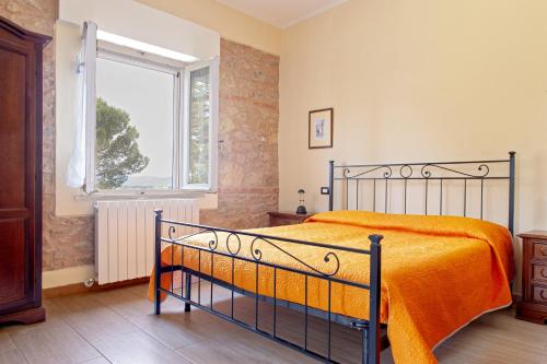 a bedroom with a bed with an orange blanket and a window at Antica Fattoria Borghesi in Fauglia