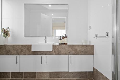 a white bathroom with a sink and a mirror at The Haven on Blue Bay in Mandurah