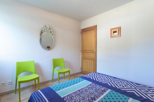 1 Schlafzimmer mit 2 grünen Stühlen und einem Bett in der Unterkunft Les Aiguilles de Chabrière - Appt vue montagne in Savines